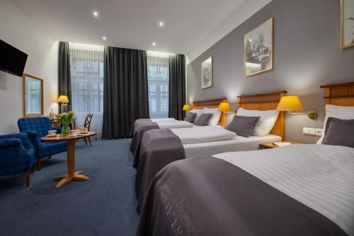 a hotel room with three beds and a table and chairs at Prague Season Hotel in Prague