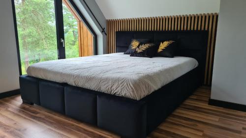 a large bed in a bedroom with a large window at Mazurskie Wzgórze Nad Jeziorem Isąg in Pelnik