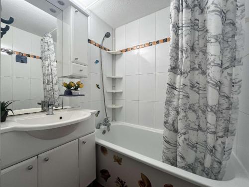 une salle de bain avec un lavabo et un rideau de douche dans l'établissement Maison 2 pièces/mezzanine, 6 couchages, terrasse spacieuse, piscine et parking privé à Gruissan - FR-1-229-332, à Gruissan