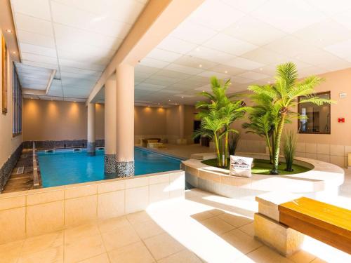 une piscine dans le hall de l'hôtel avec des palmiers dans l'établissement Appartement 6 pers avec piscine, sauna et terrasse - Saint-Lary-Soulan centre - FR-1-296-498, à Saint-Lary-Soulan