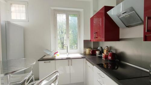 une cuisine avec des armoires blanches, un évier et une fenêtre dans l'établissement La Bulle du bois, à Clamart