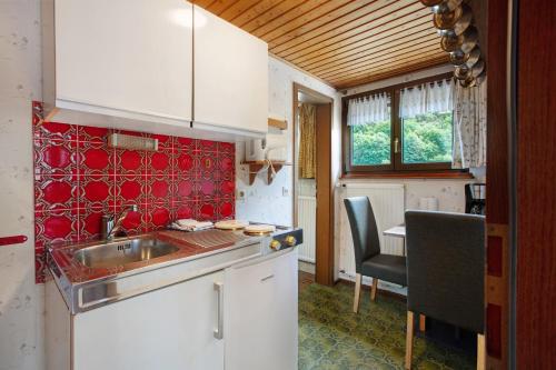 a kitchen with a sink and a table with chairs at Am Wehrastrand App Pr in Todtmoos