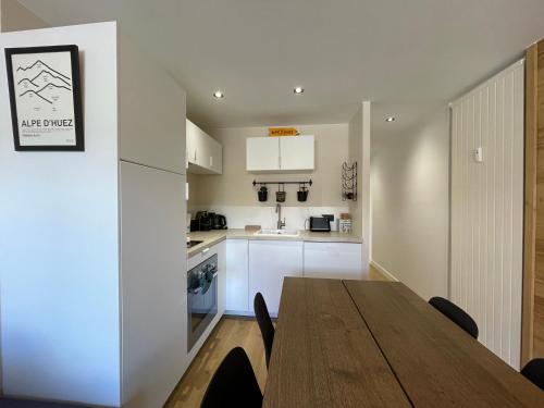 une cuisine avec une table en bois et une salle à manger dans l'établissement Homency - Résidence Hélios A1, à L'Alpe-d'Huez