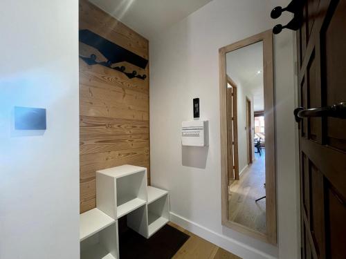 un couloir avec des étagères blanches et un miroir dans l'établissement Homency - Résidence Hélios A1, à L'Alpe-d'Huez