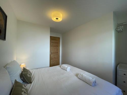 - une chambre dotée d'un lit blanc avec une lumière au plafond dans l'établissement Homency - Résidence Hélios A1, à L'Alpe-d'Huez