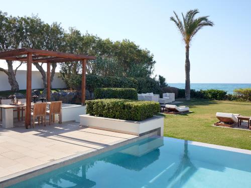 a villa with a swimming pool and a patio at Amirandes, A Grecotel Resort to Live in Gouves