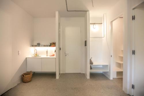 a white bathroom with a sink and a door at Convent-Βand Αpartment in Kalabaka