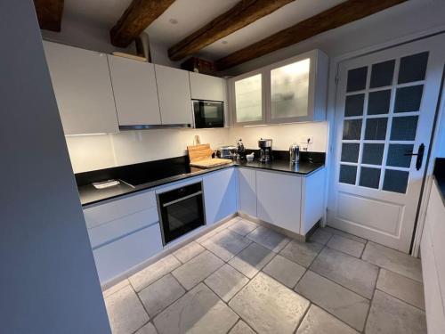 une cuisine avec des armoires blanches et un sol carrelé dans l'établissement Villa Portillon - charming fountain garden villa, à Luchon