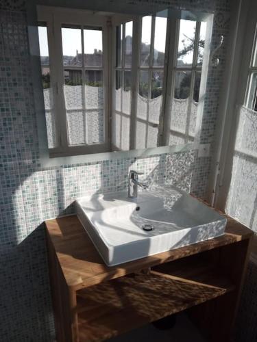 La salle de bains est pourvue d'un lavabo blanc et de fenêtres. dans l'établissement Stilvolle Villa 300 Meter vom Meer, à Lacanau-Océan