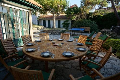 une table en bois avec des chaises et une table pour un repas dans l'établissement Stilvolle Villa 300 Meter vom Meer, à Lacanau-Océan