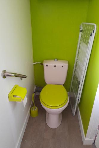 une salle de bain verte avec des toilettes avec un siège jaune dans l'établissement Maison au calme en pleine nature à Bourbriac, à Bourbriac