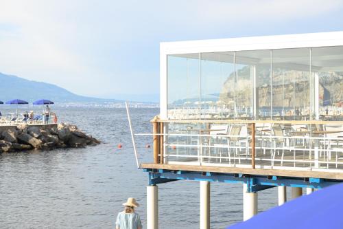 a person walking next to a pier with a building at Parco dei Principi in Sorrento