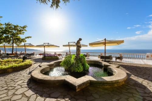 a fountain with a statue in front of the ocean at Parco dei Principi in Sorrento