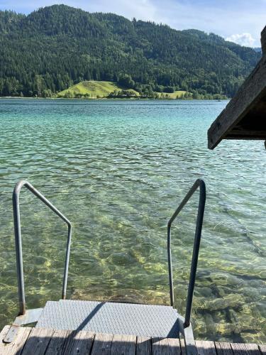 a bench sitting on the end of a dock on a lake at Pferdehof Rupitsch - Haus Carina in Weissensee
