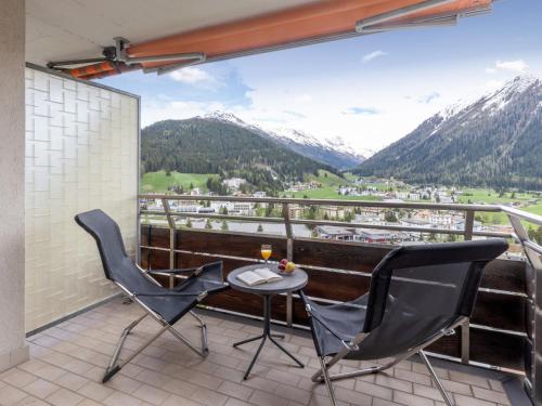 a balcony with two chairs and a table and mountains at Apartment Guardaval Apt 308 by Interhome in Davos
