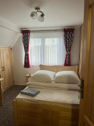 a bedroom with a bed and a window with red curtains at Pokoje u Magdusi przy termach in Witów