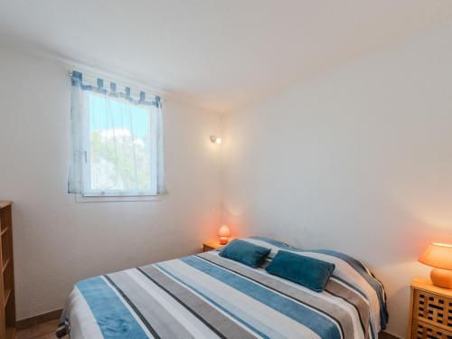 une chambre avec un lit avec des oreillers bleus et une fenêtre dans l'établissement Apartment Les Exals by Interhome, à Saint Pierre La Mer