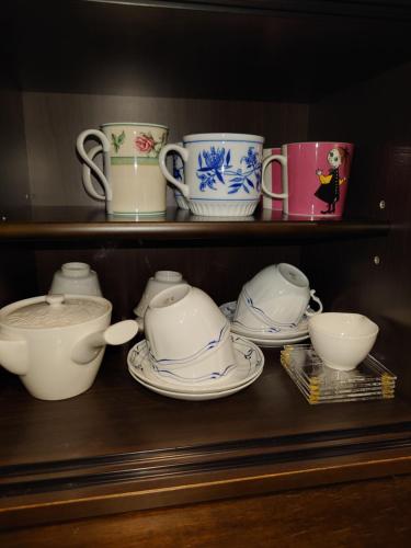 a shelf with cups and plates and bowls on it at ゲストハウス長閑 in Toyooka