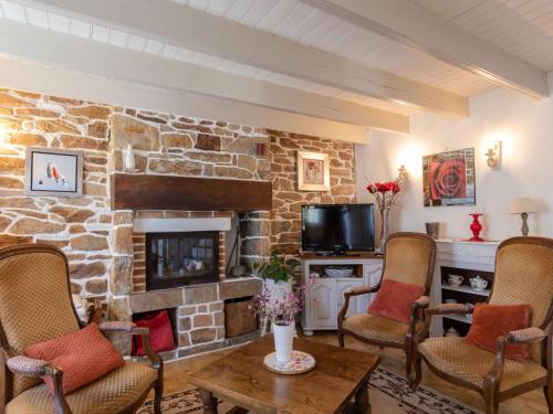 - un salon avec une cheminée en pierre et des chaises dans l'établissement Holiday Home Les Hortensias by Interhome, à Kerherneau