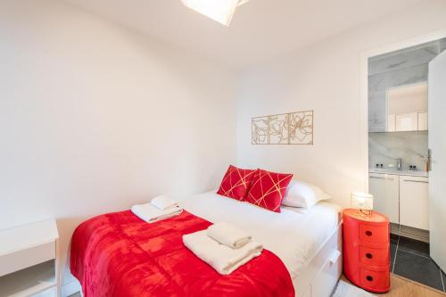 - une chambre avec un lit rouge et blanc et 2 serviettes dans l'établissement Spacious and bright 2-bedroom large apartment very close to Paris - near metro, à Boulogne-Billancourt