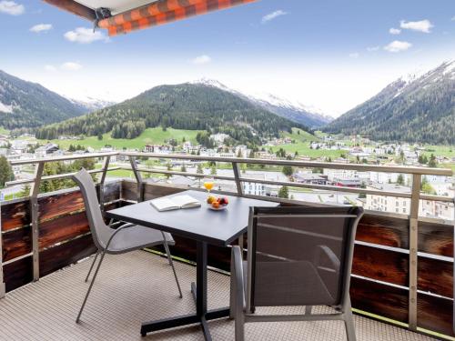 a table and chairs on a balcony with mountains at Apartment Guardaval Apt 107 by Interhome in Davos