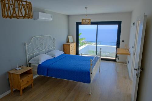 a bedroom with a blue bed and a large window at Villa Aleph-Kiralık Müstakil havuzlu lüx villa in Bodrum City