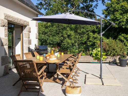 - une table en bois avec un parasol sur la terrasse dans l'établissement Holiday Home Les Menhirs by Interhome, à Ploumilliau