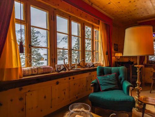 a room with a chair and a window with a mountain view at Chalet Traumhaus in Arosa