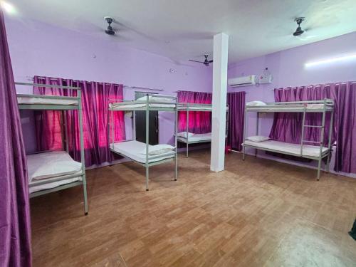 a room with four bunk beds with pink curtains at Ayodhya Stays & Cafe in Faizābād
