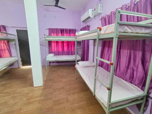 a room with three bunk beds with pink curtains at Ayodhya Stays & Cafe in Faizābād