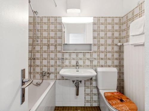 a bathroom with a sink and a toilet and a mirror at Apartment Guardaval - Utoring-36 by Interhome in Davos