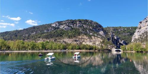 three people on boats in a river with a mountain at Côté Verdon in Quinson