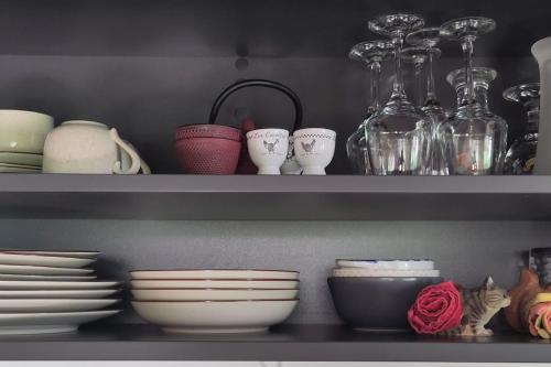 une étagère avec des bols, des assiettes et d'autres plats dans l'établissement La Maisonnette Bleue, Eco-logis équipé de toilettes sèches, à Rosheim