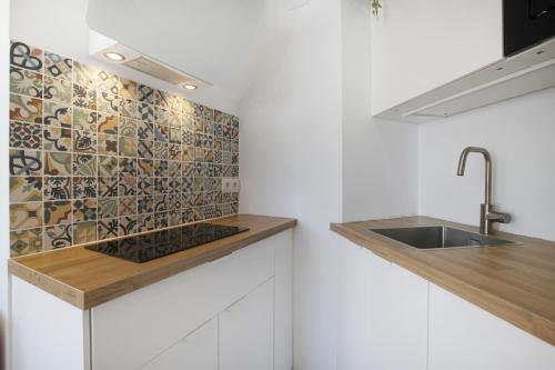 eine Küche mit einer Spüle und einer Fliesenwand in der Unterkunft Plata Ático in Torremolinos