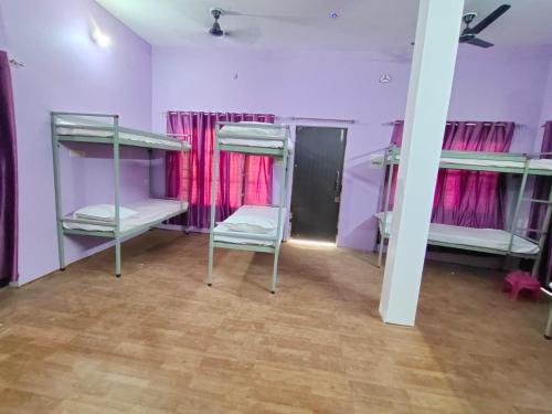 a room with three bunk beds in a purple room at Ayodhya Stays & Cafe in Faizābād