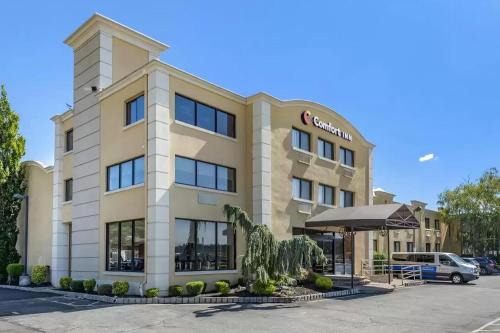 a hotel building with an umbrella in a parking lot at Comfort Inn Edgewater on Hudson River in Edgewater