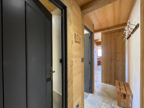 drzwi otwarte w korytarzu z drewnianymi ścianami w obiekcie Homency - Résidence Saint Laurent C1 w LʼAlpe-dʼHuez