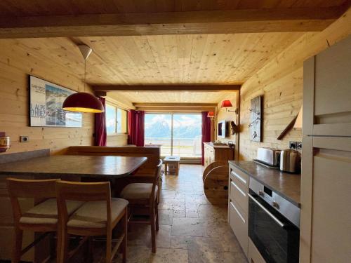 une cuisine avec une table et des chaises dans une pièce dans l'établissement Homency - Résidence Saint Laurent C1, à L'Alpe-d'Huez