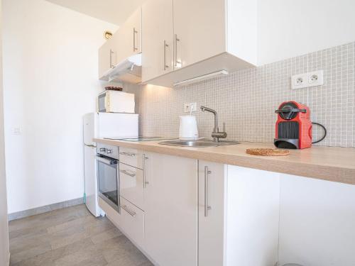 une cuisine avec des armoires blanches et un évier dans l'établissement Apartment Le Trident by Interhome, à Cannes