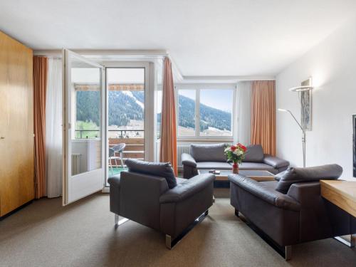 a living room with leather furniture and a large window at Apartment Parkareal - Utoring-49 by Interhome in Davos
