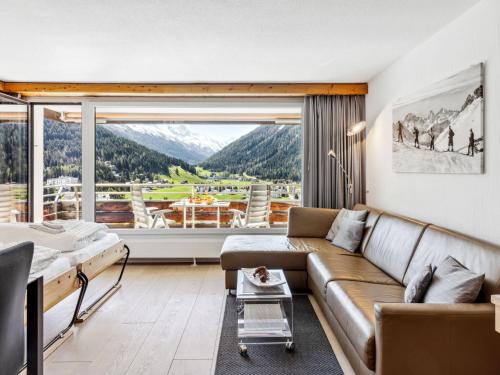 a living room with a couch and a large window at Apartment Guardaval - Utoring-66 by Interhome in Davos
