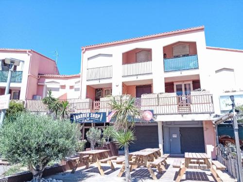 un bâtiment avec des tables et des chaises devant lui dans l'établissement Apartment Le Méditerranée-2 by Interhome, au Barcarès