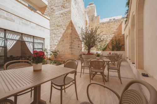 an outdoor patio with tables and chairs and windows at Maria Rosa Suites in Victoria