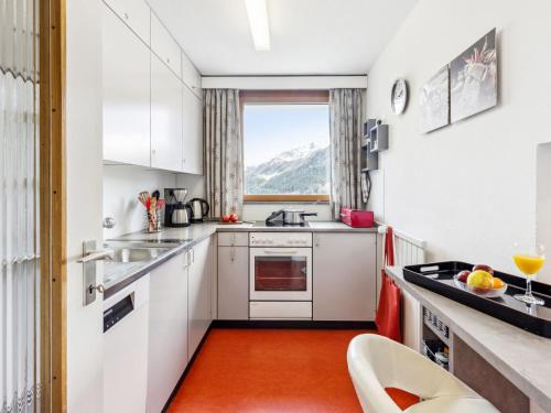 a kitchen with white cabinets and an orange floor at Apartment Guardaval - Utoring-44 by Interhome in Davos