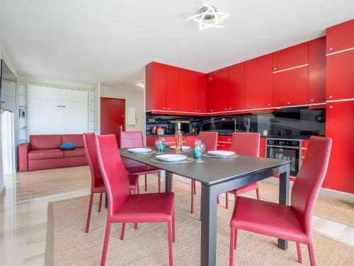 une cuisine avec des placards rouges, une table noire et des chaises rouges dans l'établissement Apartment La Croix des Gardes by Interhome, à Cannes