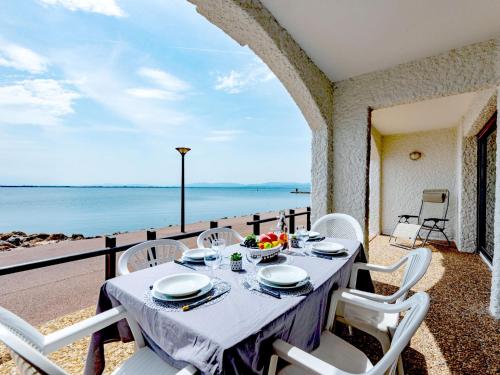 - une table avec des chaises blanches et une vue sur l'océan dans l'établissement Apartment Coudalère-Guadeloupe-3 by Interhome, au Barcarès