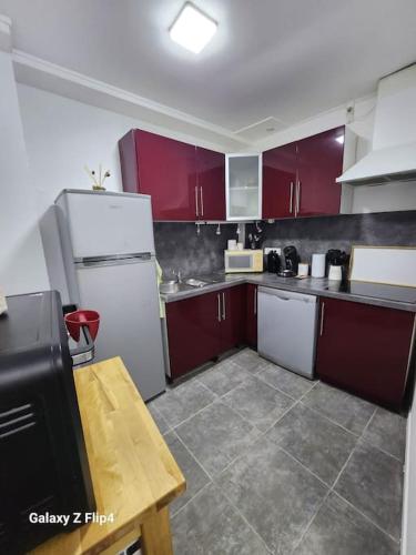 une cuisine avec des armoires rouges et un réfrigérateur blanc dans l'établissement le Côme-ci, comme ça, à Fécamp