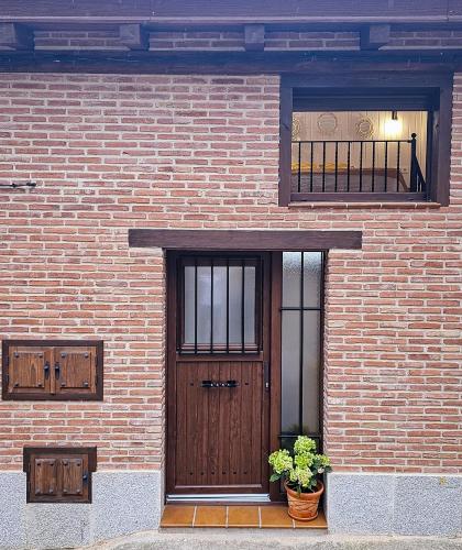 a brick building with a wooden door and two plants at Triana in Villarejo del Valle