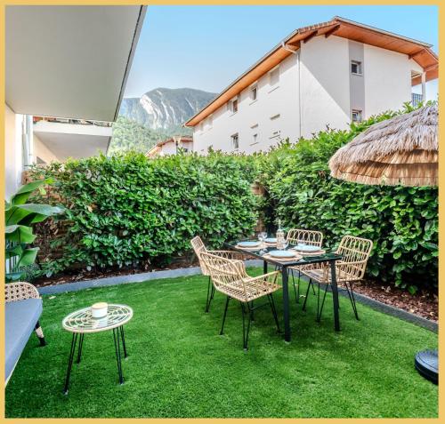 a patio with a table and chairs on the grass at Le Paradis Tropical in Scionzier