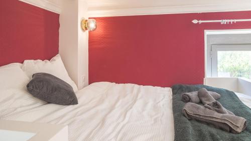 a bed with two towels and a red wall at BonAppart 2 - Charme Napoléonien & Confort in Troyes